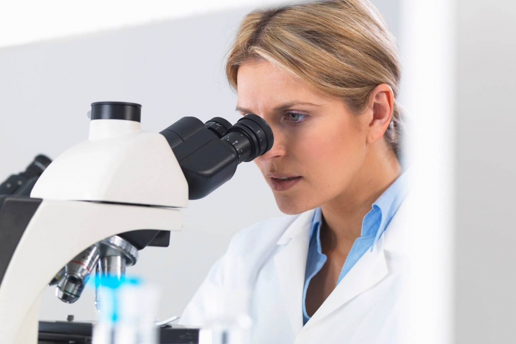 Scientist looking into a microscope, representing Aragen's large molecule (biologics) services
